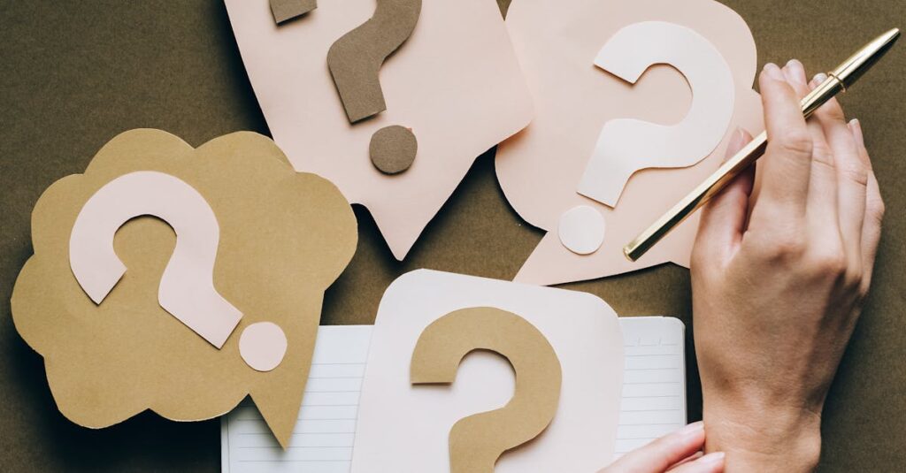 pexels-photo-5428833-5428833 Hands holding pen next to paper question marks on notebook, symbolizing inquiry and creativity.