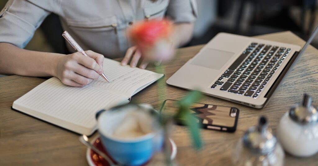 pexels-photo-1766604-1766604-2 Woman writing in a notebook with a laptop and coffee cup on a desk. Ideal for workspace inspiration.