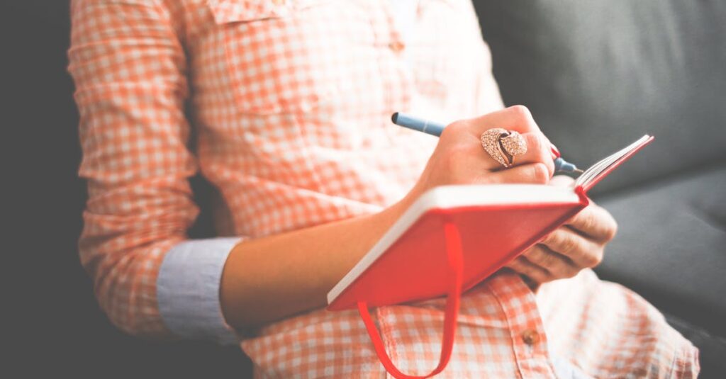 pexels-photo-261735-261735 Close-up of a woman writing in a red journal on a sofa, wearing a stylish ring.