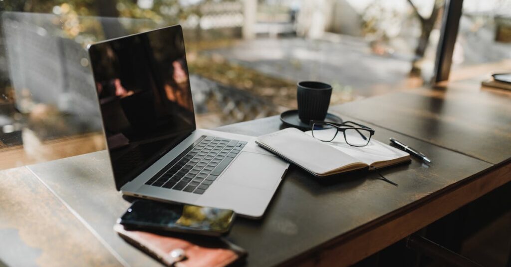 pexels-photo-5951553-5951553 A serene office setup with a laptop, notebook, and coffee near a window, reflecting an autumn scene.